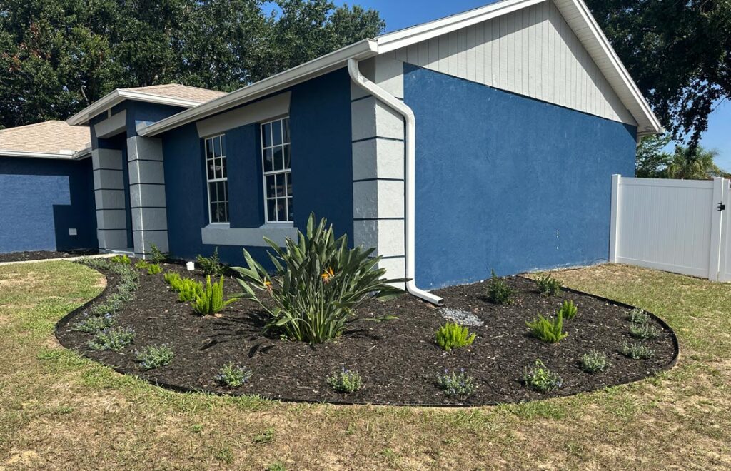 Front yard landscape design in Clermont, FL featuring ornamental trees, shrubs, fresh mulch, and clean landscape edging.